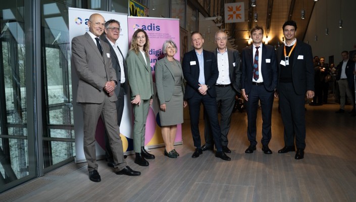 Die Bundesrätin Elisabeth Baume-Schneider steht mit dem Vorstand und dem Leiter der Geschäftsstelle von ADIS und dem Direktor vom EBGB vor Roll-up-Bannern mit dem Logo der ADIS – Allianz für Digitale Inklusion Schweiz. Sie posieren in einem modernen, lich